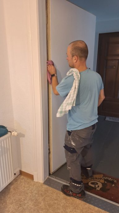 Ein Handwerker führt Renovierungsarbeiten an einer Tür durch.