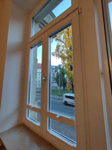Fenster mit Blick auf eine Straße und einen Baum im Herbst.